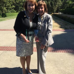 Photo: State Secretary Karen Ross and Sunne Wright McPeak stand together holding the 2018 CA State Fair Award for Individual Championstands next to her.